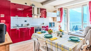 Una cocina moderna con armarios rojos, un comedor con mesa para dos y un balcón con vistas.