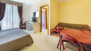 Une chambre d’hôtel comprenant un lit, un bureau avec un ordinateur, une table à manger avec des chaises et un canapé.
