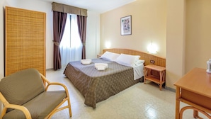 Een hotelkamer met een bed, een stoel, een tafel, een nachtkastje en een schilderij aan de muur.