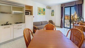 Een compacte leefruimte met een kitchenette, een eethoek en een balkon met uitzicht.