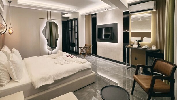 Ein modernes Hotelzimmer mit einem großen Bett, einem Schreibtisch, einem Stuhl und einem runden Tisch.