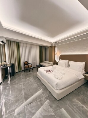 A modern hotel room with a large bed, a desk, a chair, and a sofa. - Alberello Otel (Kütahya)