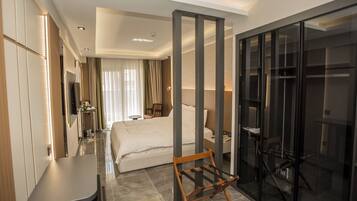 A hotel room with a bed, a desk, a wardrobe, and a glass partition.