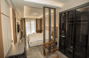 A hotel room with a bed, a desk, a wardrobe, and a glass partition. - Alberello Otel (Kütahya)