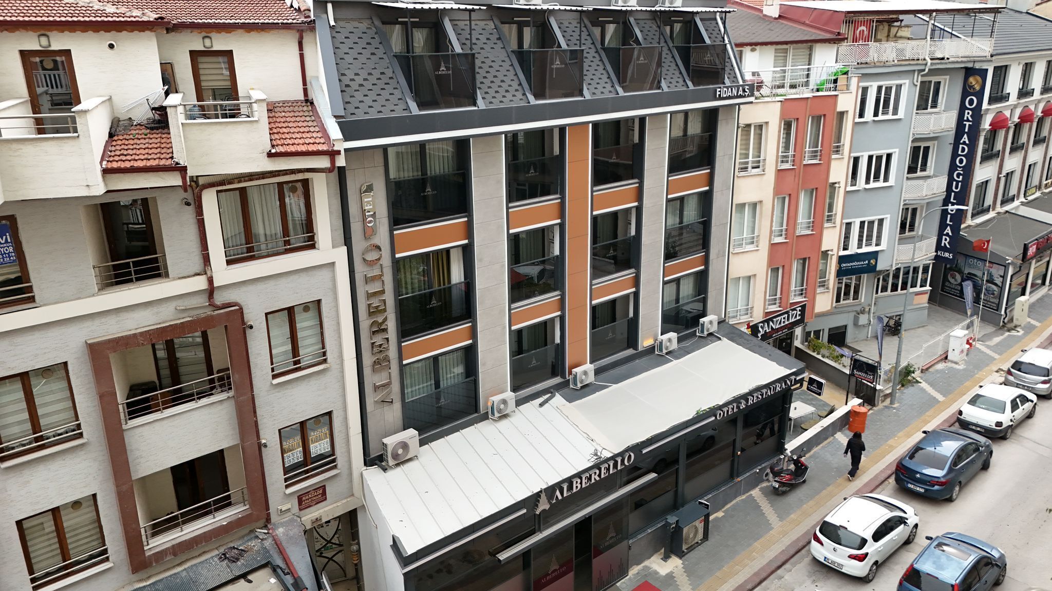 A multi-story hotel with balconies, a rooftop terrace, and a ground-level restaurant.