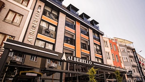 Ein mehrstöckiges Hotel mit Balkonen, einem Schild mit der Aufschrift ‚Alberello‘ und einem Restaurant im Erdgeschoss.