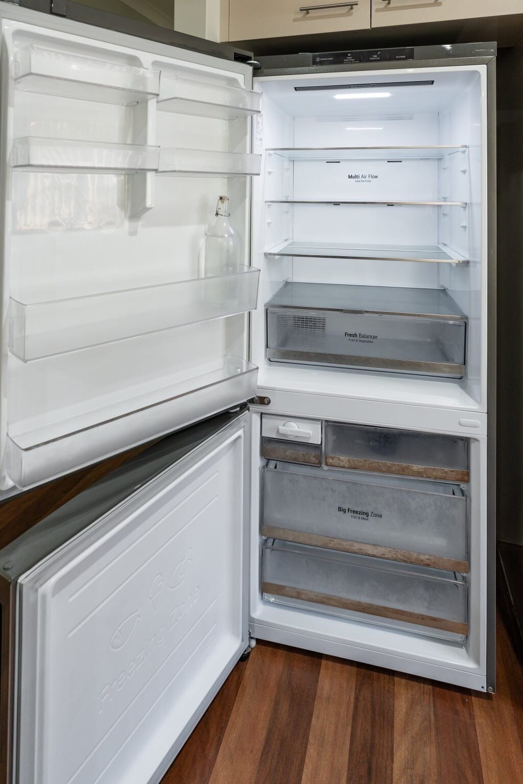 Ein offener Kühlschrank mit mehreren Ablagen und Fächern, darunter ein 'Multi Air Flow'-Bereich, ein 'Fresh Balancer' für Obst und Gemüse sowie eine 'Big Freezing Zone' für Tiefkühlprodukte.