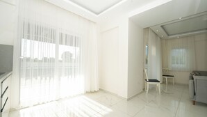 Un salón espacioso con un ventanal grande, un televisor de pantalla plana y una zona de estar con dos sillones.