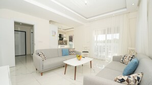 Una sala moderna con un sofá gris, una mesa de centro blanca y un cojín estampado.
