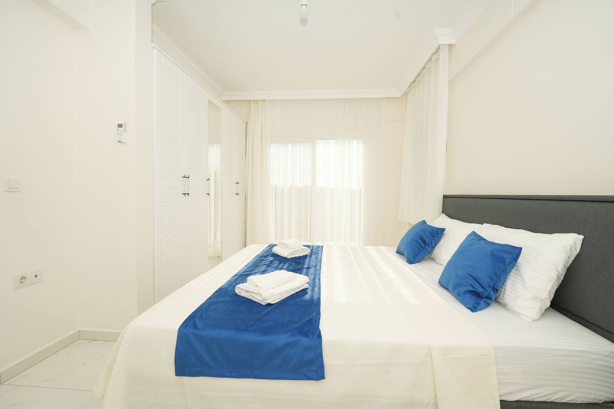 Een hotelkamer met een bed, witte gordijnen en een raam.