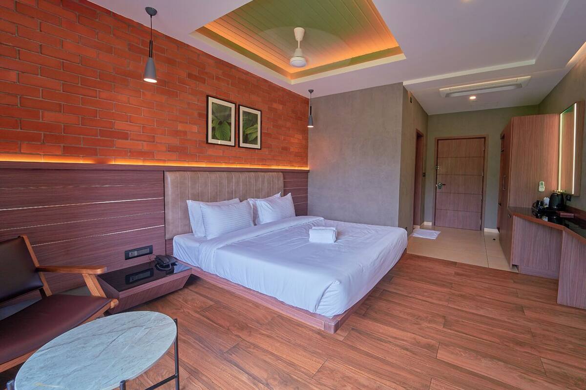 Una habitación de hotel moderna con una cama grande, un escritorio, una silla y una mesita.