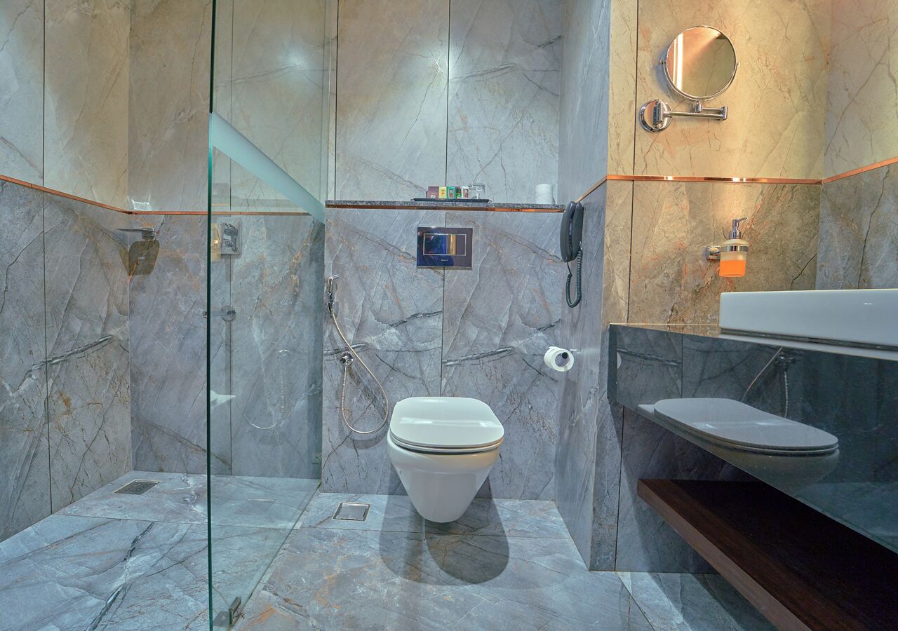 Ein modernes Badezimmer mit Marmorboden, Toilette, Duschkabine aus Glas und Waschtisch mit Spiegel.