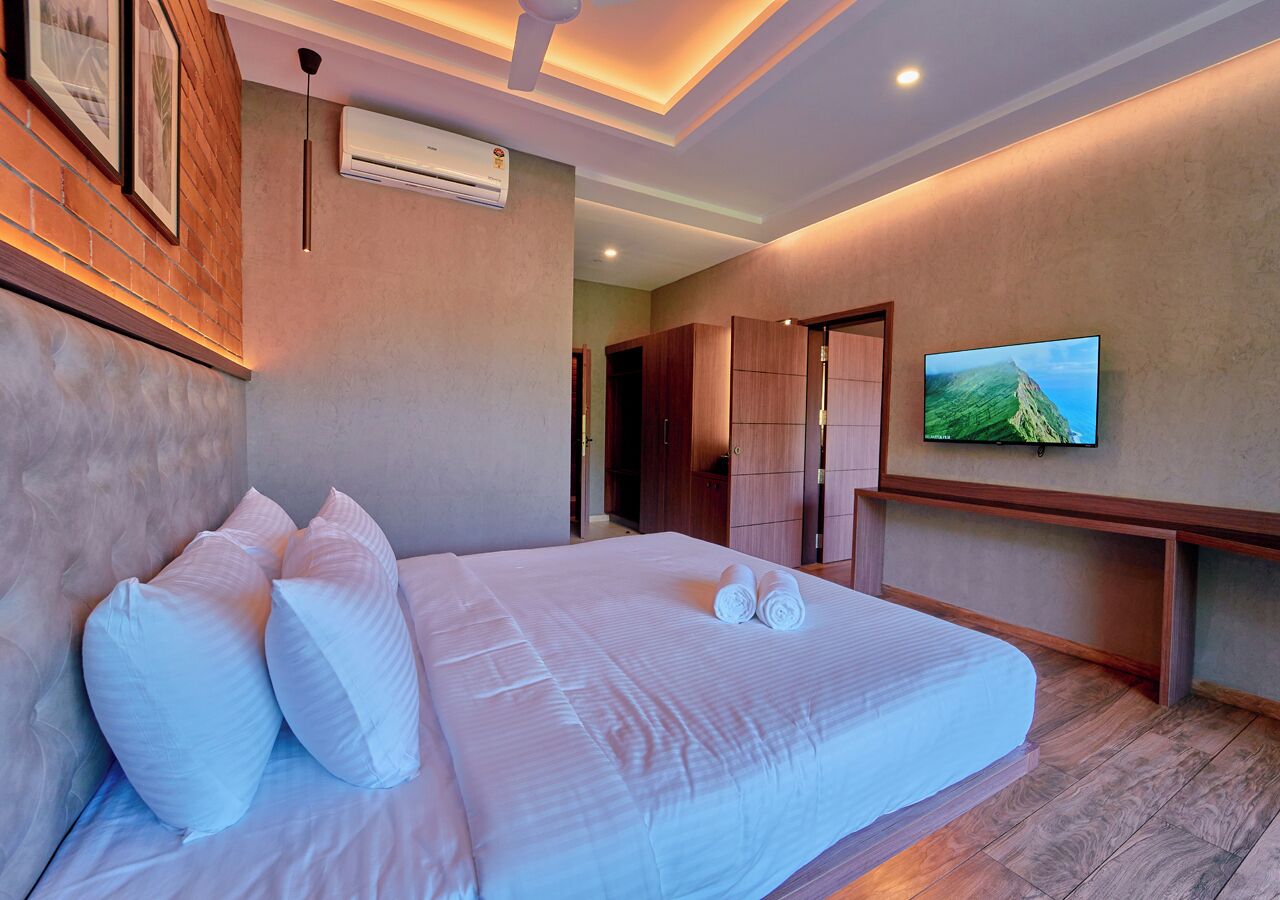 Une chambre d’hôtel avec un grand lit, un téléviseur à écran plat, des meubles en bois et un mur en briques.