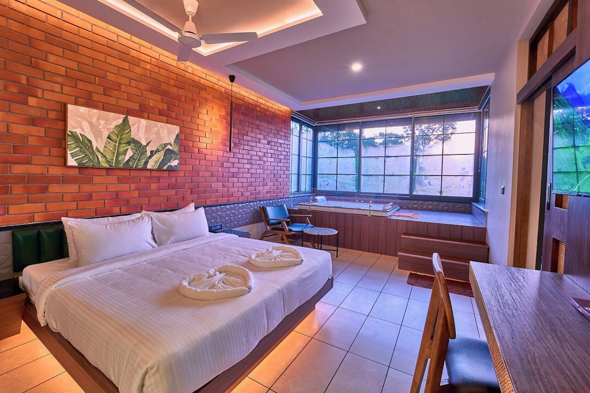 Una habitación de hotel con una cama grande, zona de estar con vistas y una mesa de comedor.