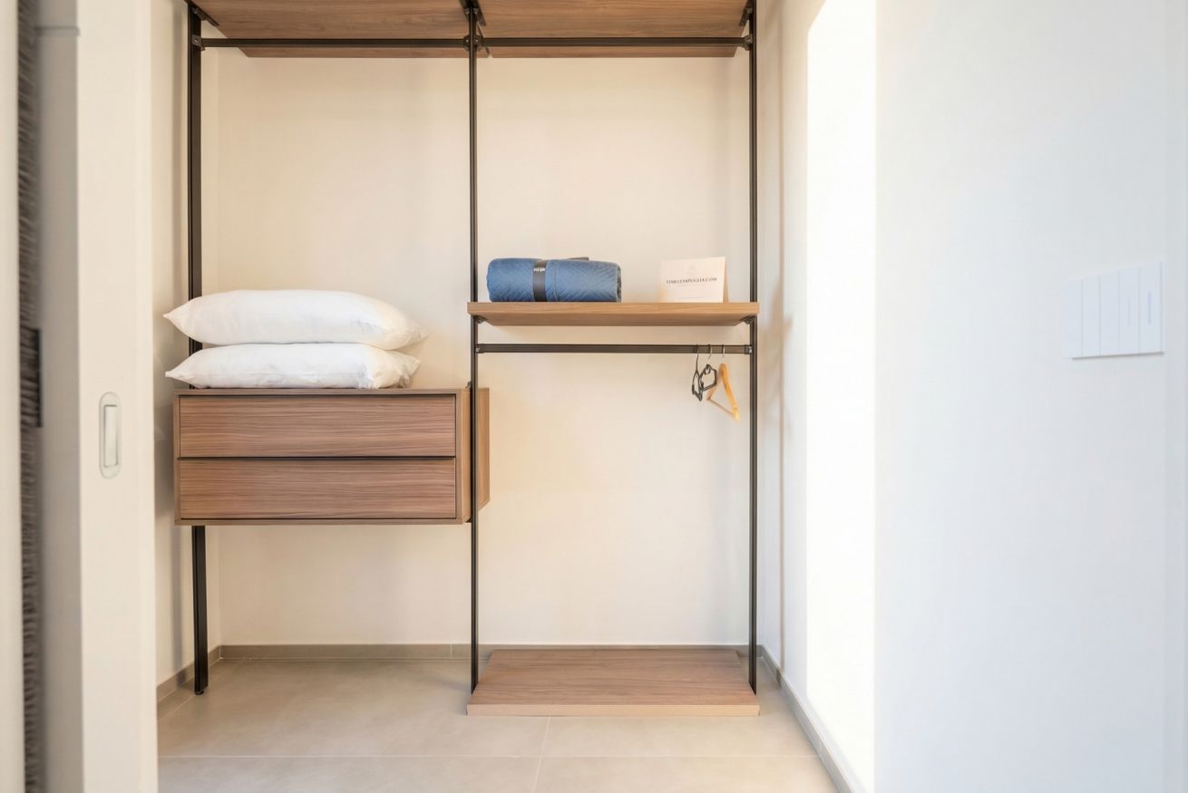 Un dressing avec un banc en bois, des étagères et un espace pour suspendre les vêtements.