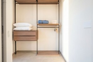 A walk-in closet with a wooden bench, shelves, and hanging space. - Panorama Penthouse Terrace with Parking (Bari)