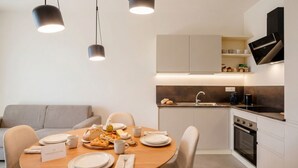Une cuisine moderne avec un coin repas, comprenant une table mise pour deux personnes, avec des assiettes, des tasses et un panier de pain.
