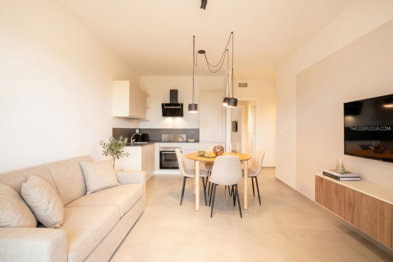 A modern living space with a sofa, dining table, and kitchen area.