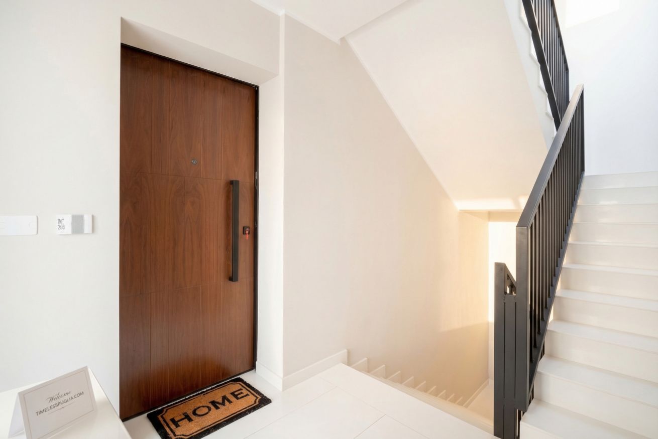 Un escalier avec une rampe noire menant à un palier.