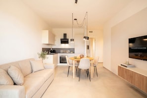 Ein modernes Wohnzimmer mit Sofa, Esstisch und Küchenzeile.