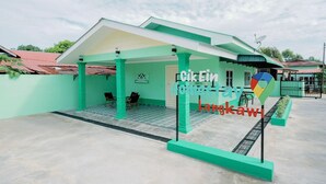 Un edificio verde con un patio cubierto, un letrero que dice "Cik Kin Homes fav Langkawi" y una antena parabólica en el techo.