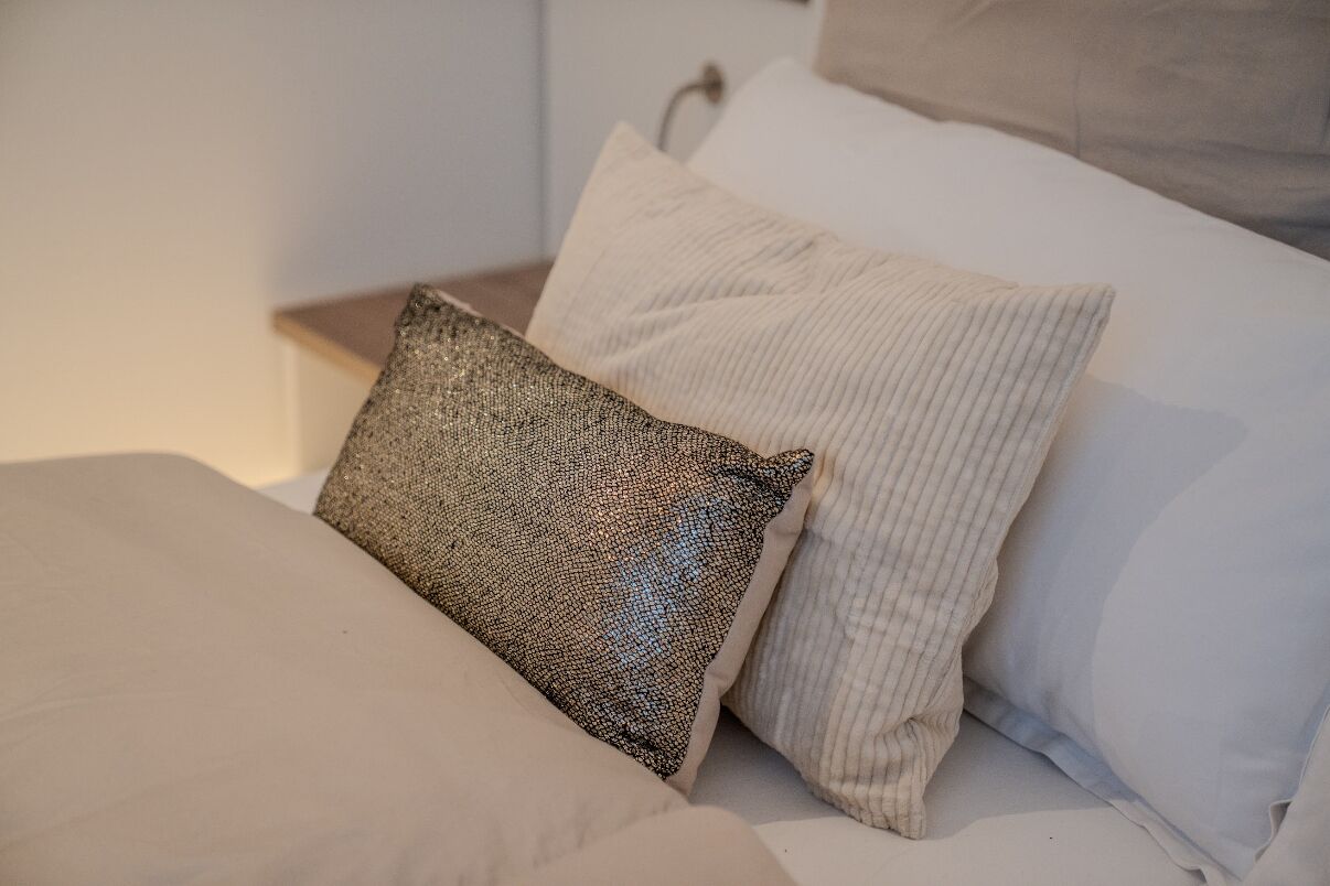 Un lit bien fait, avec deux oreillers : l’un avec un motif texturé et l’autre à motifs en relief.