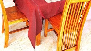 En matplats med ett bord dukat för fyra personer, trästolar och en blå soffa i bakgrunden.