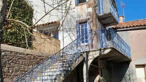 Une maison à deux étages avec un escalier en pierre et des rampes en métal bleu.