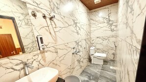 Een badkamer met een marmeren wastafel, toilet en een douchetoilet.