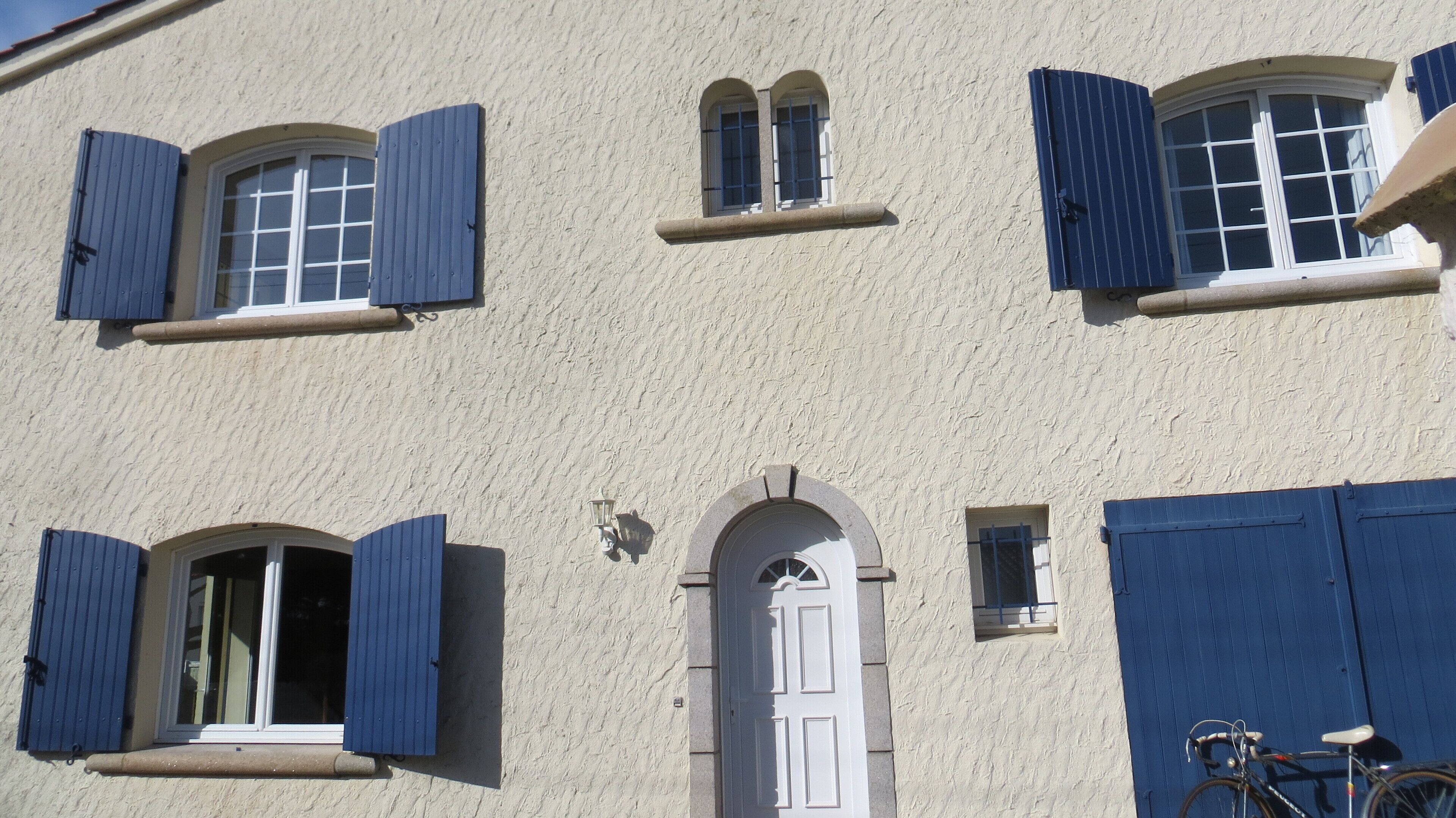 Um edifício com várias janelas, algumas com persianas, e uma porta central.