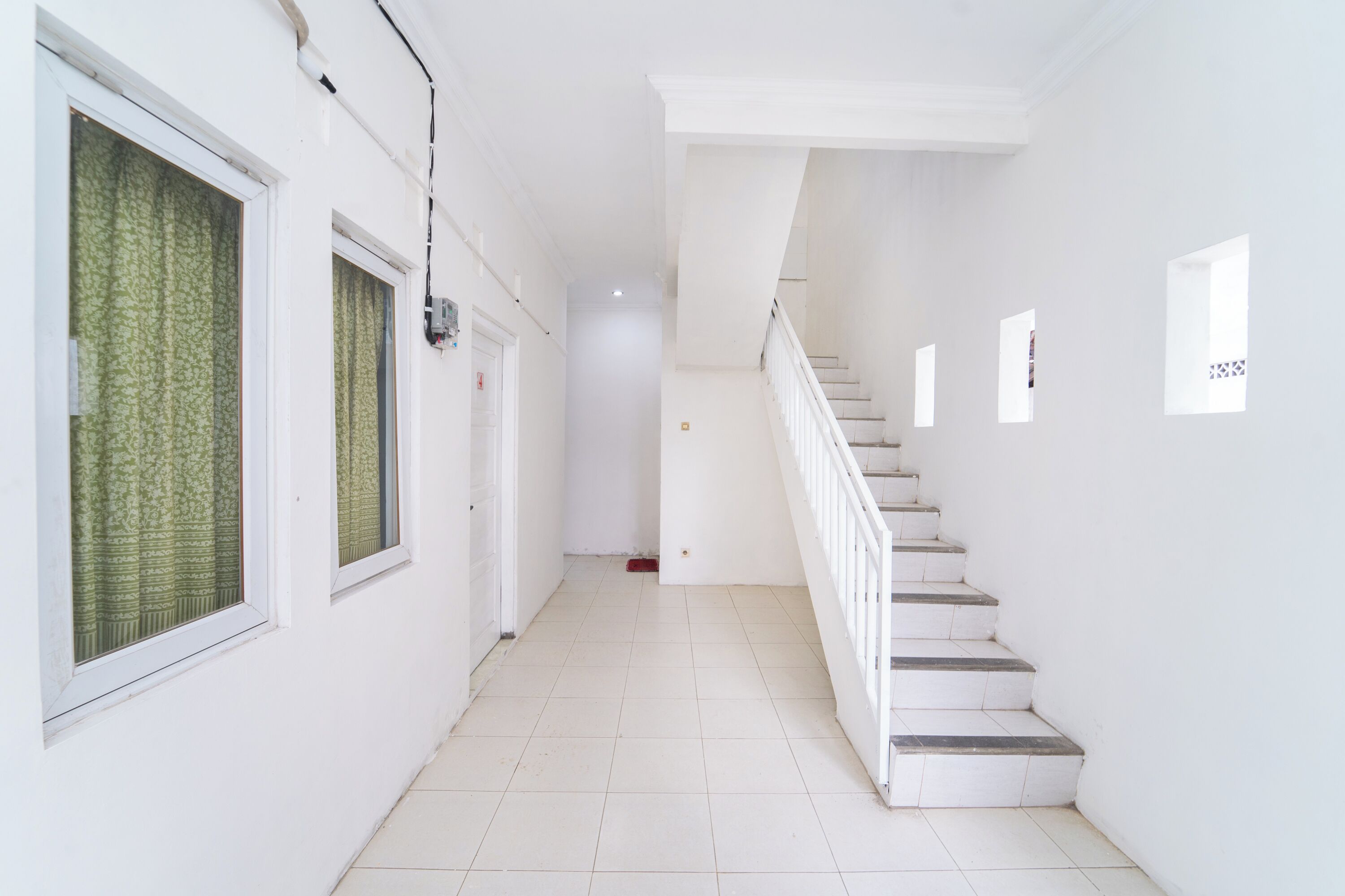 A clean, white hallway with a staircase leading to an upper floor.