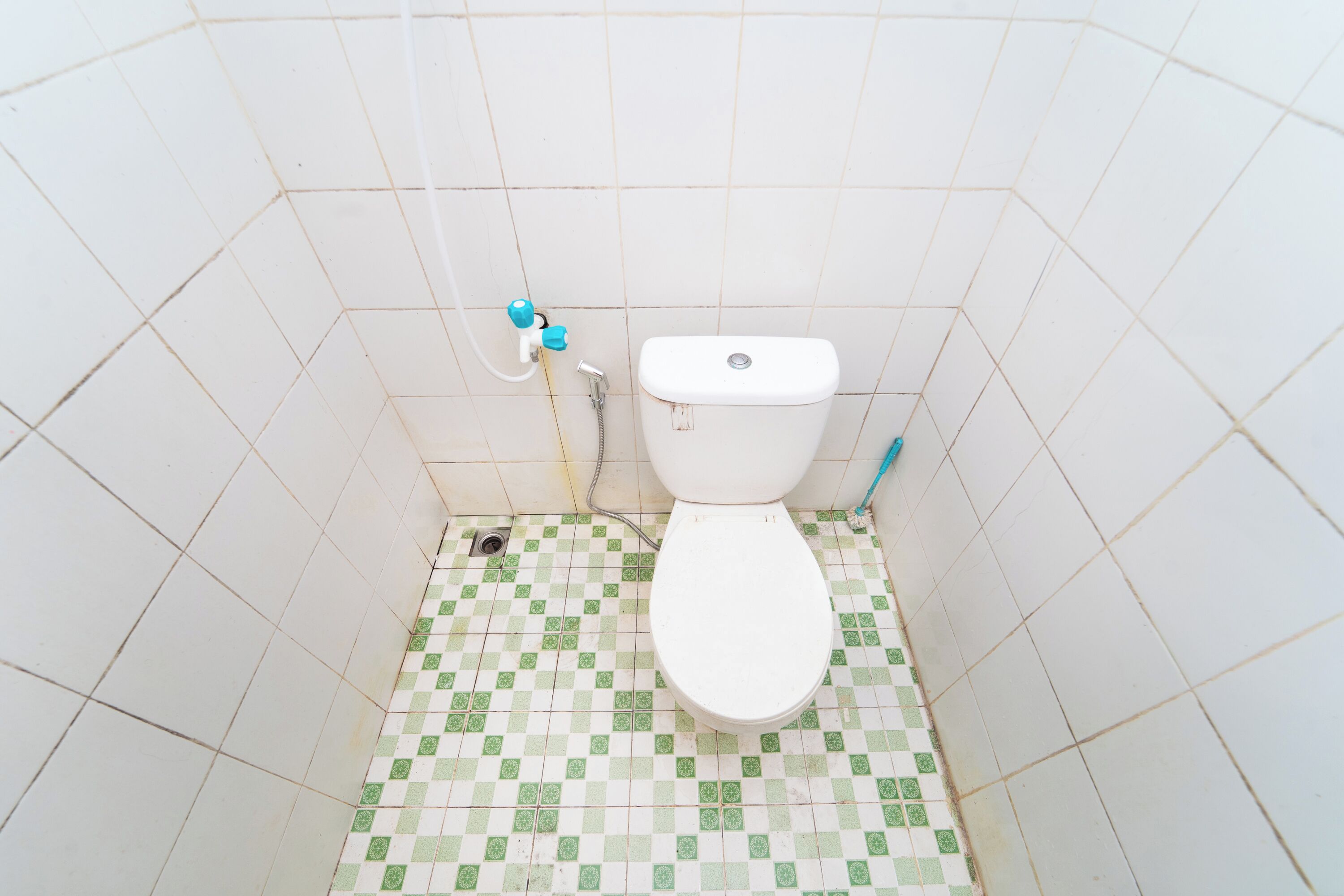 A small, tiled bathroom with a toilet, a shower, and a sink.