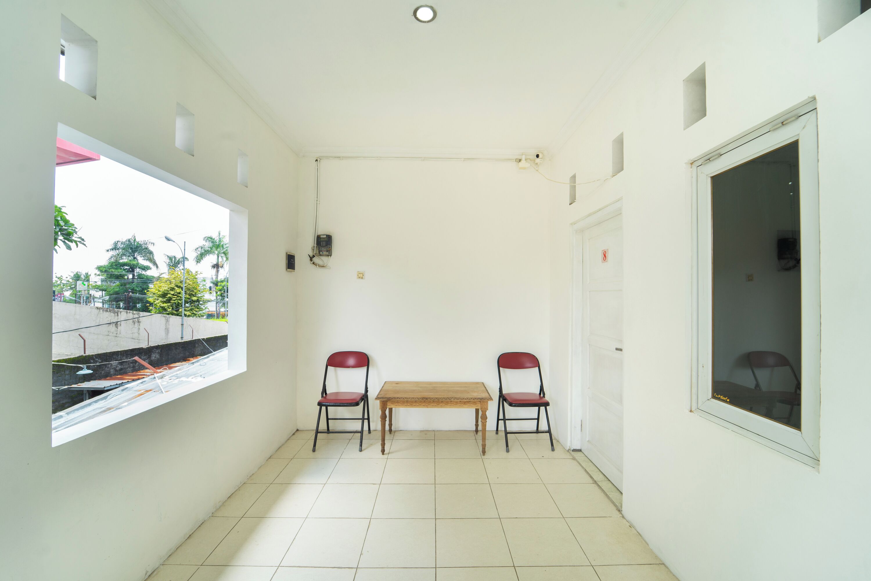 A small, clean room with a window, two chairs, a table, and a door.