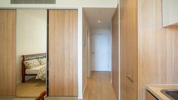 A modern bedroom with a bed, wooden wardrobe, and a kitchen area with a sink.