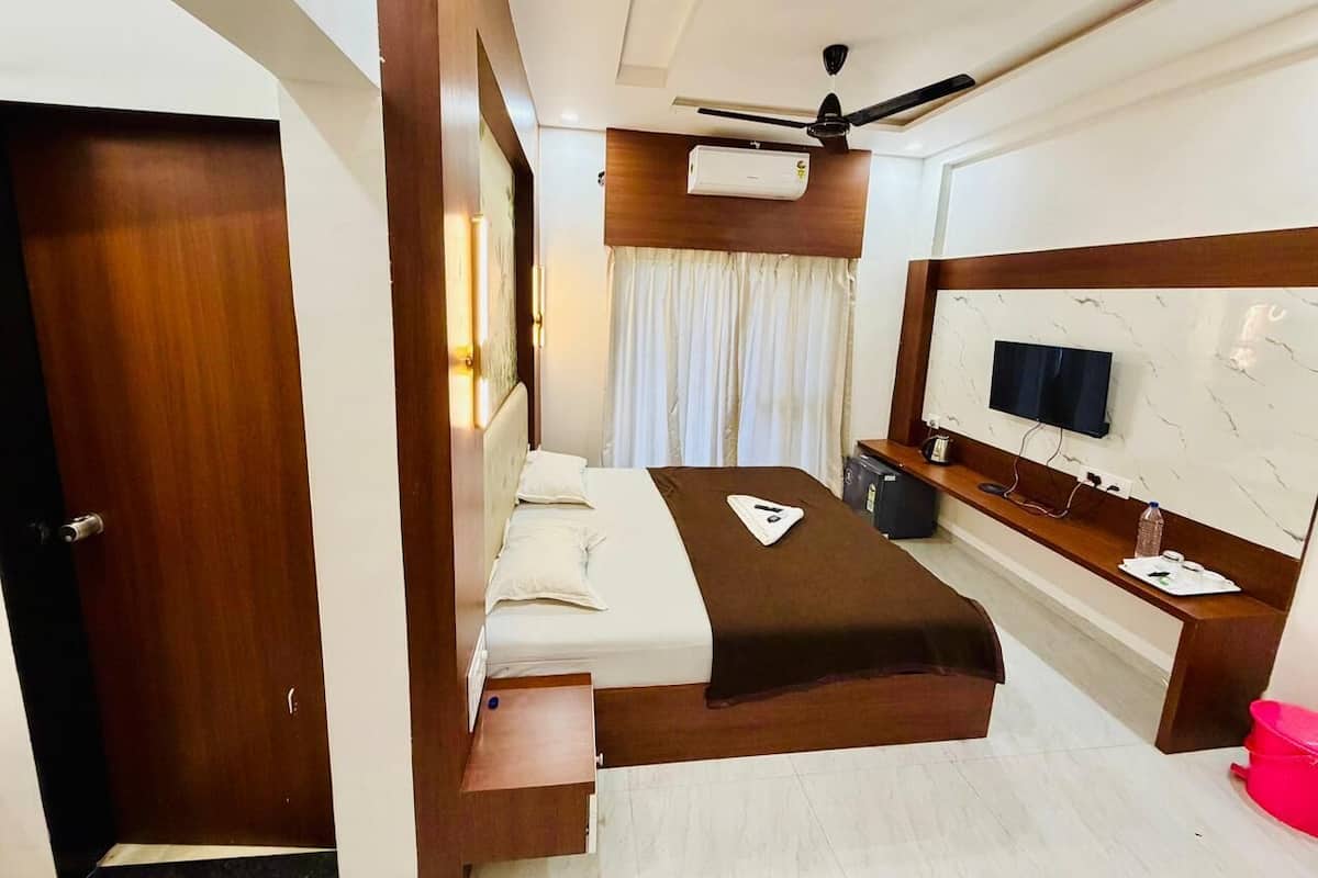 Une chambre d’hôtel équipée d’un lit, d’un bureau, d’une télévision et d’un ventilateur de plafond.