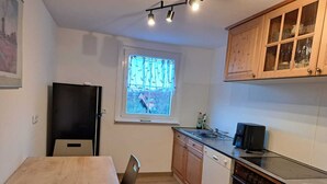 Cocina compacta con una mesa de madera, refrigerador, ventana con vista y lavavajillas.