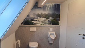 Un baño moderno con un mural tipo cascada, un inodoro y un orinal.