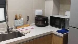 Een moderne keuken met een spoelbak, aanrecht, magnetron en koffiezetapparaat.