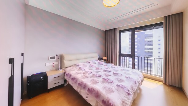 Een moderne slaapkamer met een groot bed, een nachtkastje, een kledingkast en een raam met uitzicht op gebouwen.