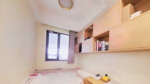 Een kleine, netjes ingerichte kamer met een bed, een bureau en een raam.