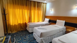 Une chambre d’hôtel avec deux lits, une moquette à motifs et un rideau jaune.