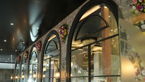 Un restaurant doté de fenêtres en arc de cercle, d’un éclairage intérieur et d’un mur en briques.