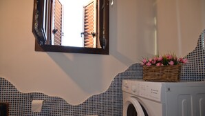 A bathroom with a washing machine, a mirror, and a window with shutters. - Fsl-quas01 in San Lorenzo (Budoni)