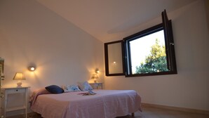 A bedroom with a bed, bedside tables, lamps, and a window with an open blind. - Fsl-quas01 in San Lorenzo (Budoni)