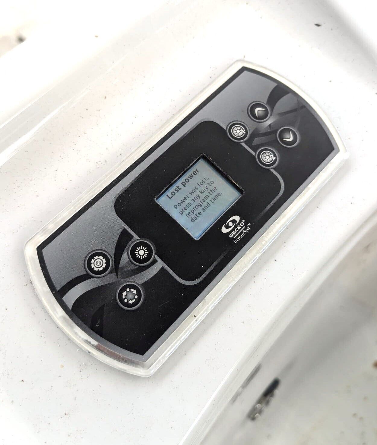 A GECKO inYourSpa control panel with a message indicating lost power and instructions to press any key to reprogram the date and time.