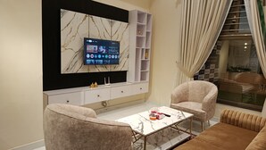 A modern living room with a marble TV wall, a white entertainment unit, and plush seating.