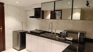 Una cocina moderna con microondas integrado, un fregadero con escurreplatos y un refrigerador de acero inoxidable.