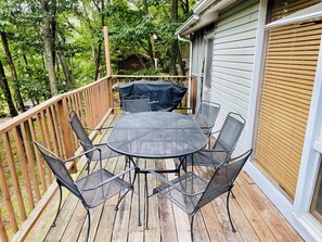 A wooden deck with a round table and six chairs, surrounded by a wooden railing. - Charming Mid-Century Cabin - Warm, Cozy & Scenic (Fort Loudon)
