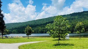 A paved path curving through a grassy area with a lake and forested hills in the background. - Charming Mid-Century Cabin - Warm, Cozy & Scenic (Fort Loudon)