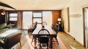 A dining area with a wooden table and chairs, a ceiling fan, and a window with blinds. - Charming Mid-Century Cabin - Warm, Cozy & Scenic (Fort Loudon)